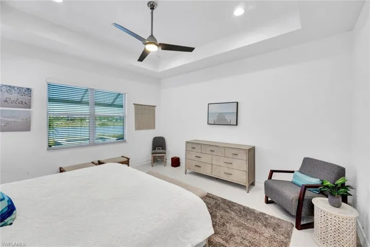 Bedroom with a ceiling fan, a raised ceiling, and recessed lighting