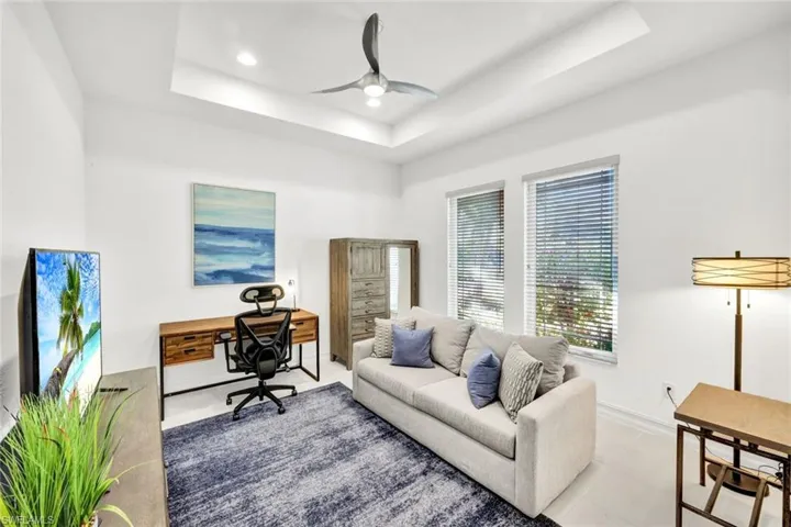 Tiled office with ceiling fan, a raised ceiling, and recessed lighting