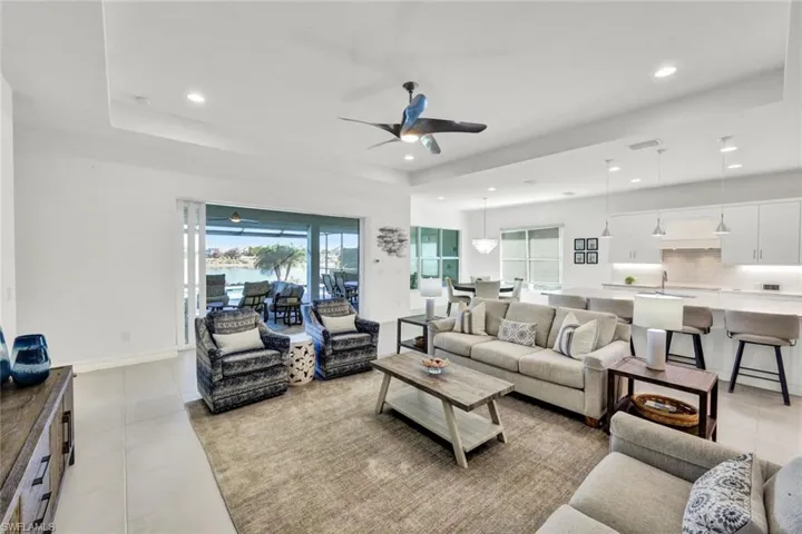 Living area featuring ceiling fan, light tile patterned floors, a tray ceiling, and recessed lighting