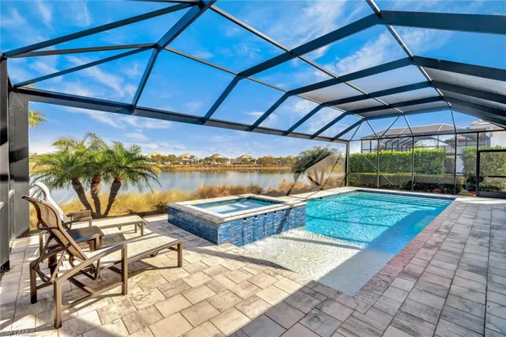 Relaxing pool / spa featuring a lanai, a sunroom, a patio, and a water view