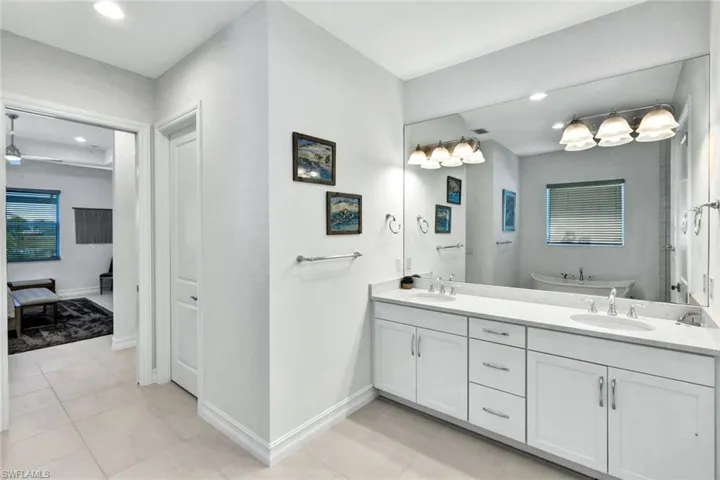 Bathroom with double vanity, light tile patterned floors, a freestanding bath, and recessed lighting