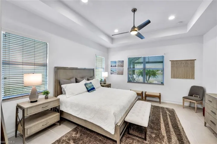 Bedroom with light tile patterned floors, ceiling fan, recessed lighting, and a raised ceiling