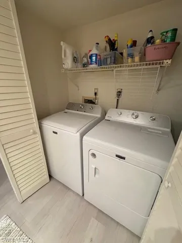 Washroom with light wood-type flooring and separate washer and dryer