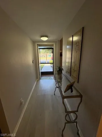 Hall featuring light wood finished floors and a textured wall
