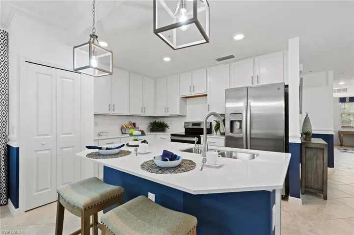 Kitchen featuring stainless steel appliances, white cabinetry, light countertops, pendant lighting, and light tile patterned flooring