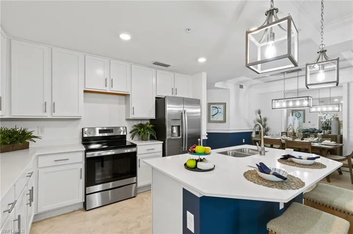Kitchen featuring appliances with stainless steel finishes, a breakfast bar area, light countertops, white cabinets, and recessed lighting