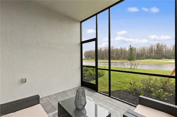 Sunroom with a water view and view of wooded area