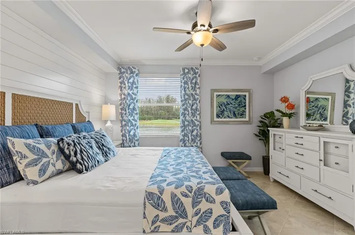 Bedroom featuring ornamental molding, a ceiling fan, wooden walls, and light tile patterned flooring