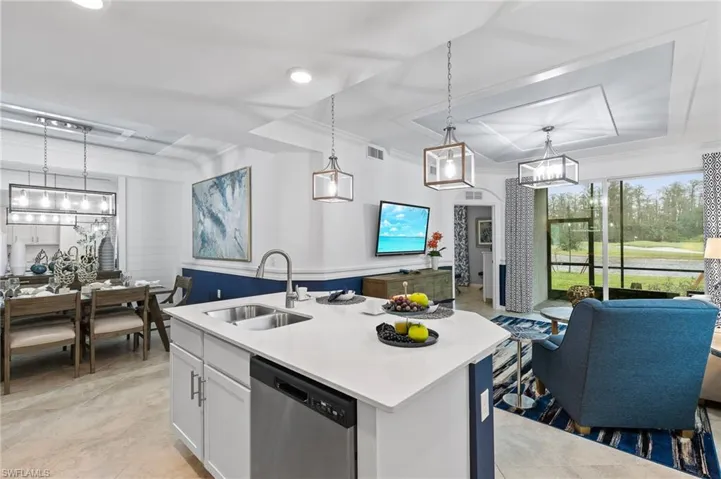 Kitchen with stainless steel dishwasher, a raised ceiling, a chandelier, crown molding, and open floor plan