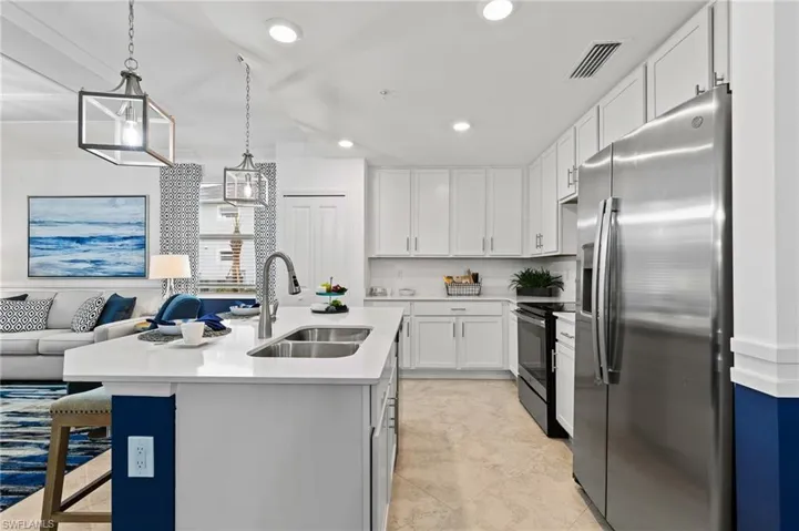 Kitchen with stainless steel refrigerator with ice dispenser, range with electric stovetop, light countertops, white cabinets, and recessed lighting
