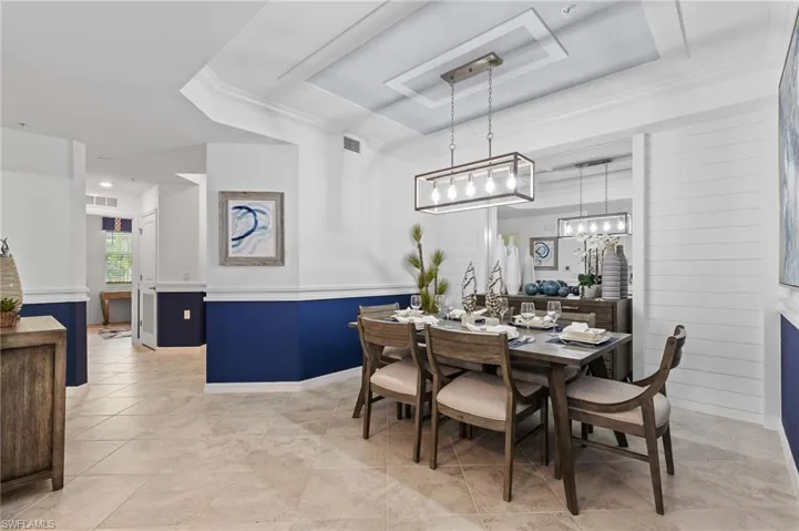 Dining space featuring a tray ceiling, light tile patterned floors, crown molding, and a chandelier