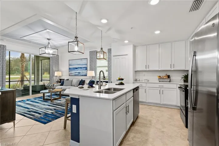 Kitchen featuring stainless steel appliances, light countertops, white cabinetry, a center island with sink, and recessed lighting