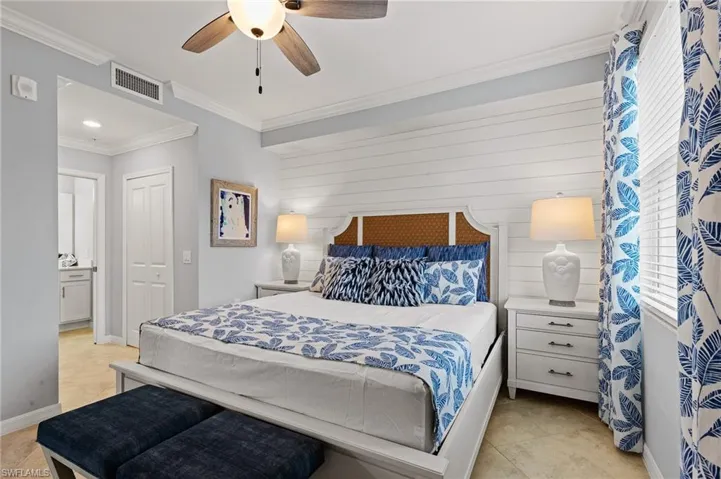 Bedroom with ornamental molding, light tile patterned floors, a ceiling fan, a closet, and wooden walls