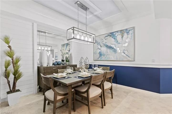 Dining space with a chandelier, a raised ceiling, and tile patterned floors