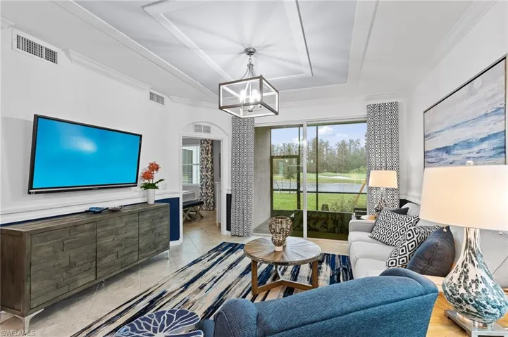 Living room featuring a raised ceiling, ornamental molding, and a chandelier