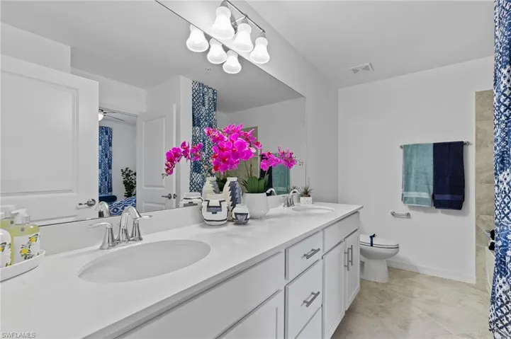 Bathroom with double vanity, ceiling fan, and tile patterned flooring