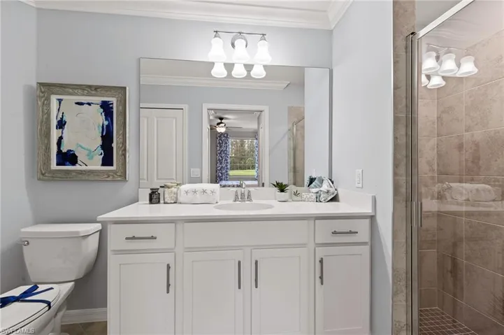 Bathroom with crown molding, vanity, a stall shower, and a ceiling fan