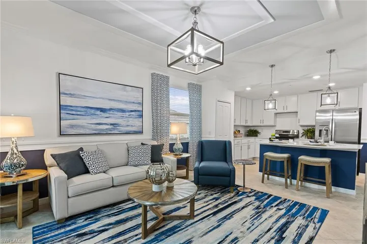 Living room with a chandelier, crown molding, recessed lighting, light tile patterned floors, and a tray ceiling
