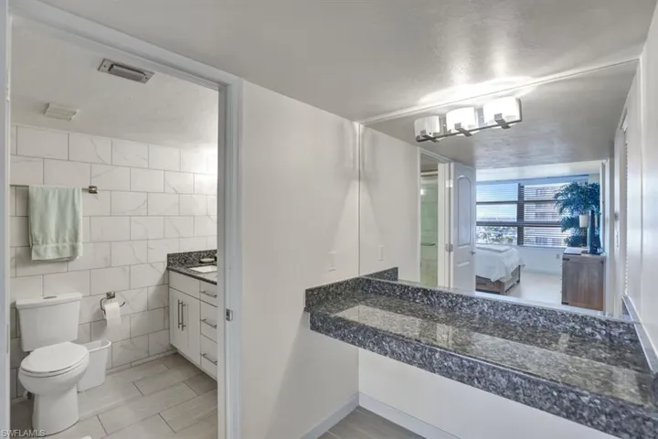 Bathroom featuring vanity, toilet, tile walls, and a chandelier