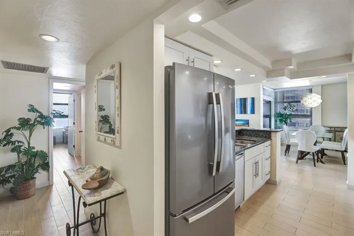 Kitchen featuring dark stone counters, white cabinets, a breakfast bar area, light hardwood / wood-style flooring, and stainless steel appliances
