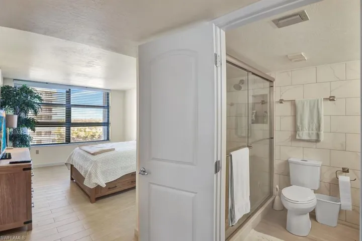 Bathroom with hardwood / wood-style floors, a textured ceiling, toilet, and an enclosed shower