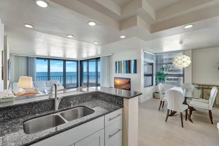 Kitchen featuring light wood-type flooring, sink, decorative light fixtures, dark stone countertops, and white cabinets