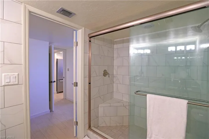 Bathroom featuring hardwood / wood-style floors, a textured ceiling, and walk in shower