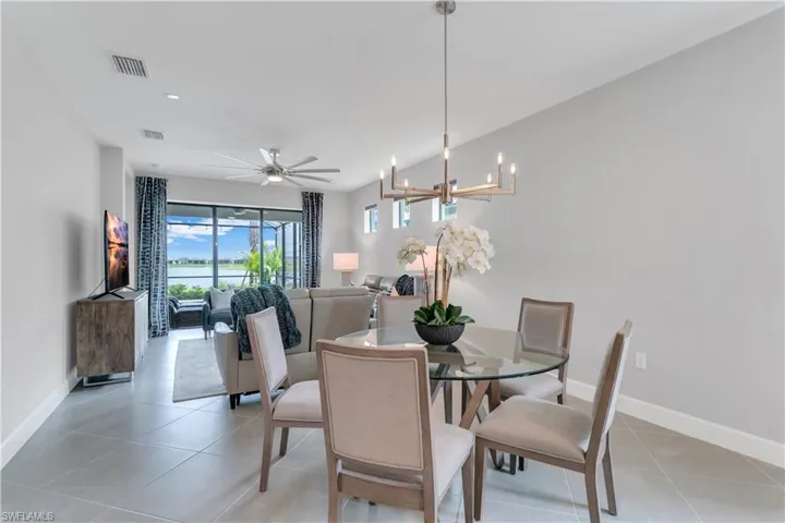 Tiled dining space with ceiling fan with notable chandelier