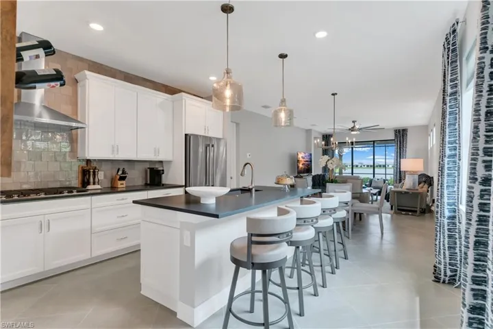 Kitchen with stainless steel appliances, ceiling fan, an island with sink, pendant lighting, and tasteful backsplash