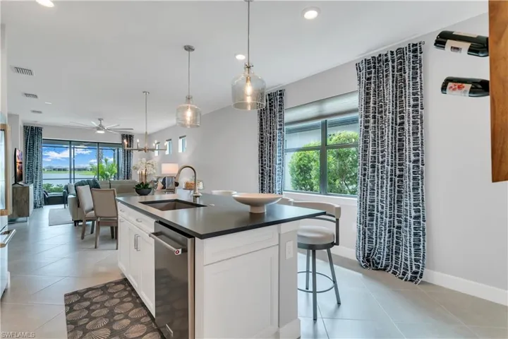 Kitchen with dishwasher, plenty of natural light, sink, and a center island with sink