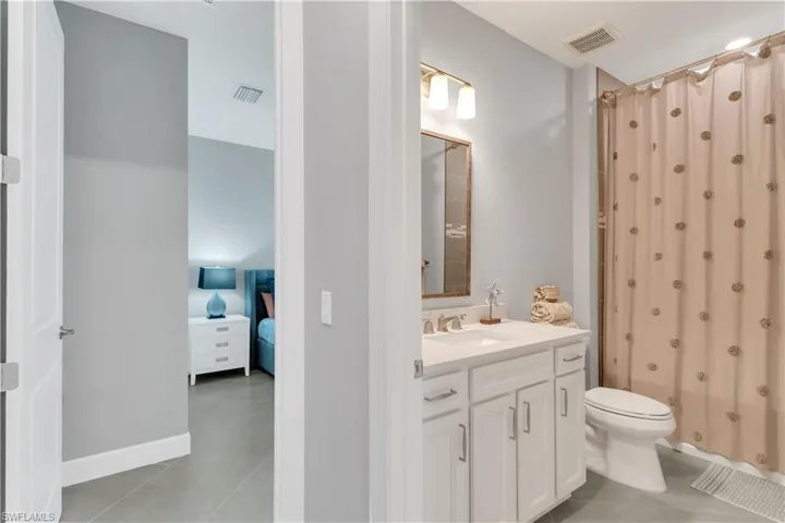 Bathroom with a shower with shower curtain, tile patterned flooring, toilet, and vanity