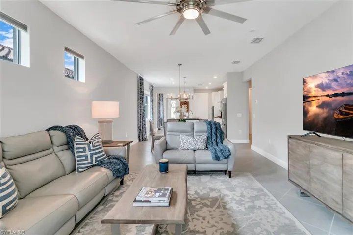 Living room with light tile patterned floors and ceiling fan with notable chandelier
