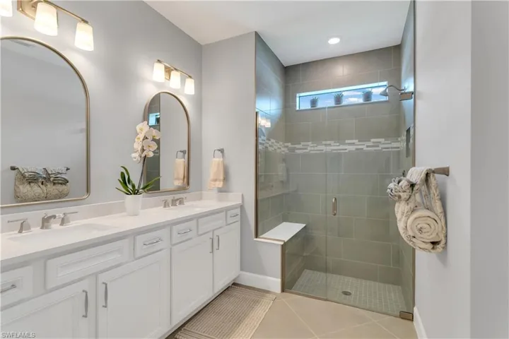 Bathroom featuring tile patterned flooring, a shower with shower door, and vanity