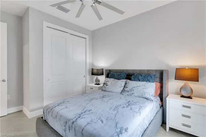Tiled bedroom featuring ceiling fan and a closet