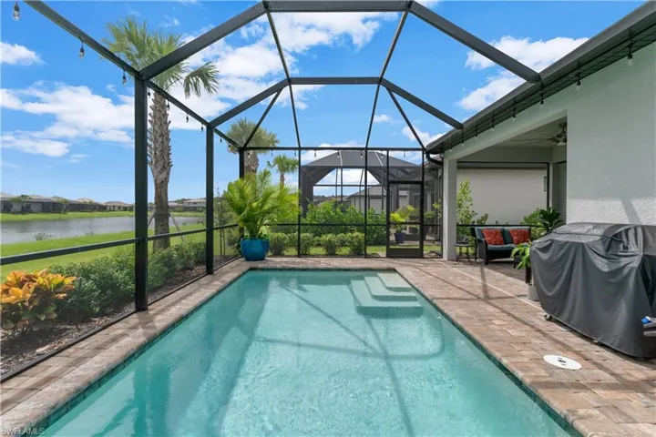 View of pool featuring a lanai, a water view, area for grilling, and a patio