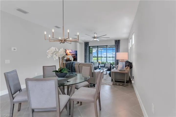 Dining room featuring ceiling fan with notable chandelier and light tile patterned floors