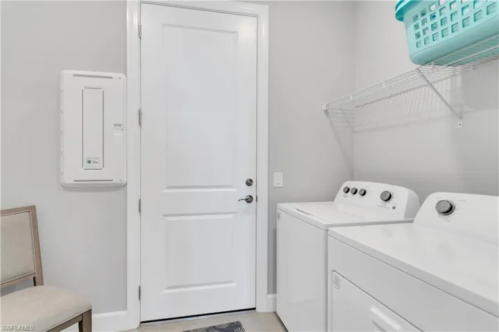 Laundry area with washing machine and clothes dryer and light tile patterned flooring