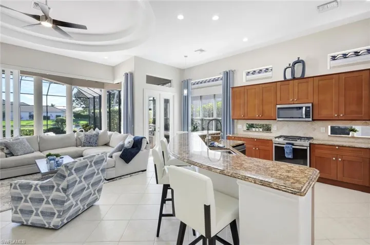 Kitchen featuring brown cabinets, recessed lighting, appliances with stainless steel finishes, a kitchen bar, and decorative backsplash