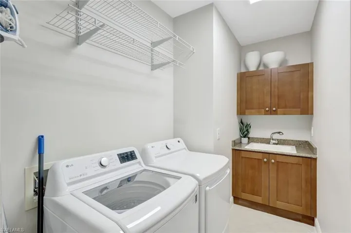 Washroom with light tile patterned floors, washer and dryer, and cabinet space