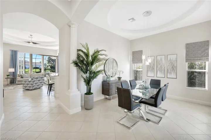 Dining room featuring a raised ceiling, decorative columns, and light tile patterned floors