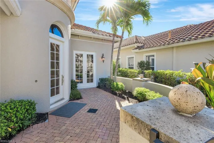 View of exterior entry featuring stucco siding, a tiled roof, and french doors