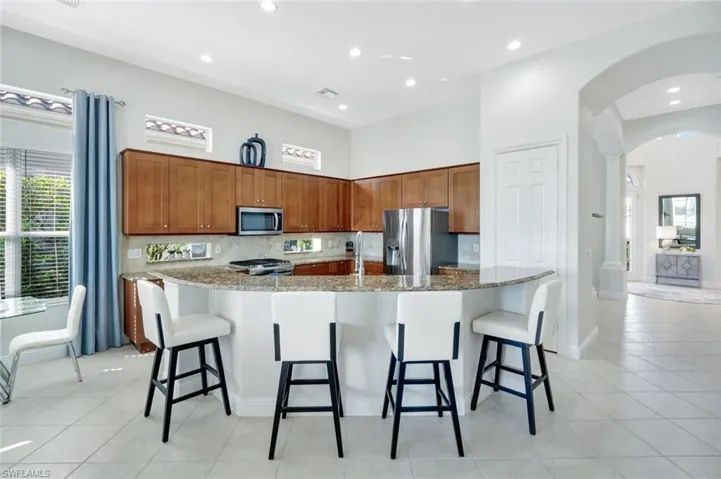 Kitchen featuring backsplash, brown cabinetry, a breakfast bar, and recessed lighting