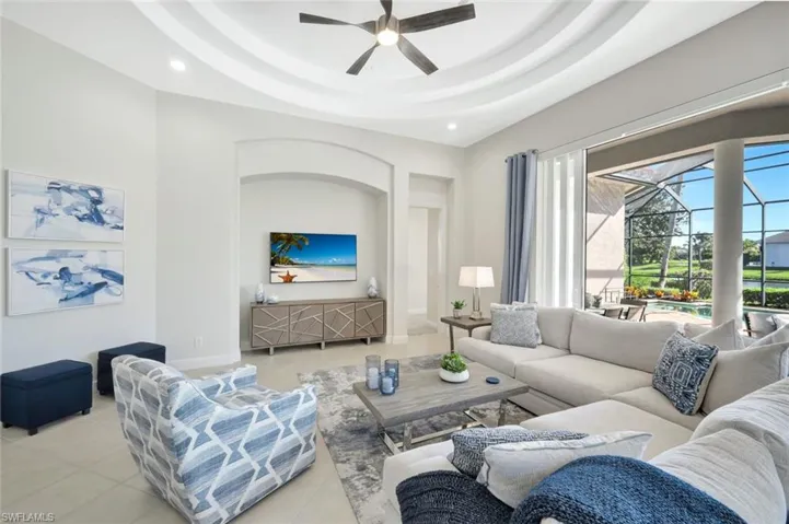 Tiled living room with ceiling fan, a tray ceiling, a sunroom, and recessed lighting