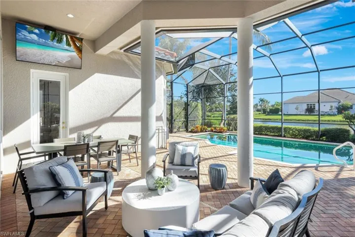 Swimming pool featuring a patio, outdoor lounge area, a water view, a sunroom, and outdoor dining space