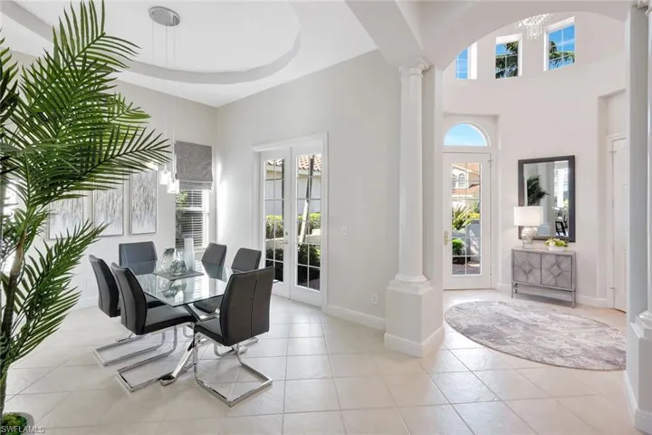 Dining area with french doors, light tile patterned floors, a towering ceiling, and a chandelier