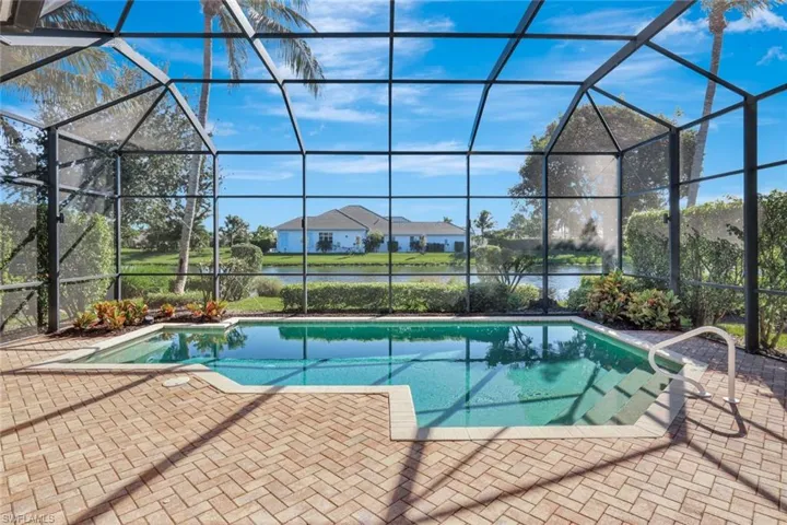 Outdoor pool with a sunroom, glass enclosure, a water view, and a patio area