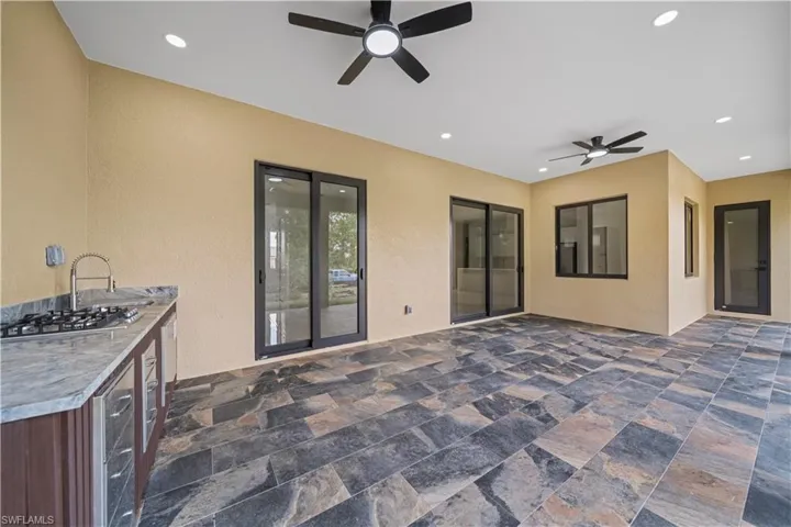 Spacious covered patio featuring multi-toned tile flooring, recessed lighting, and dual ceiling fans