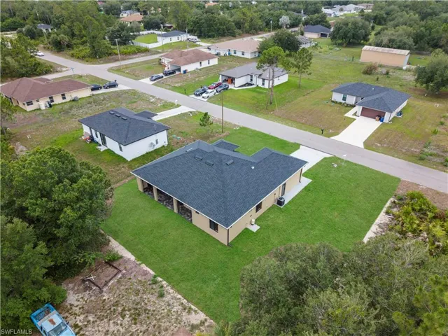 New construction home featuring a dark shingle roof, tan stucco exterior, and a spacious rear covered patio