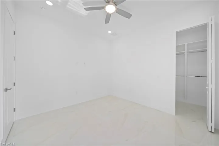 Bright interior space featuring light-toned large format tile flooring, recessed lighting, and a ceiling fan