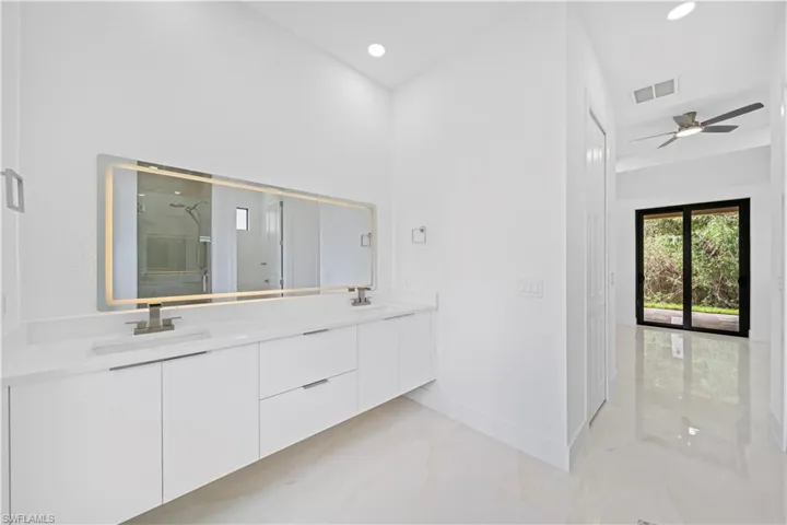 Modern bathroom vanity featuring dual sinks, a large illuminated mirror, and contemporary cabinetry